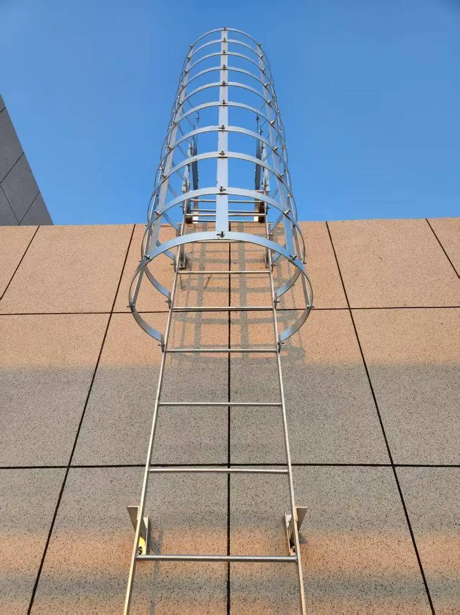 Feuerverzinkte Steigleiter mit Rückenschutz vor blauem Himmel, von unten aufgenommen